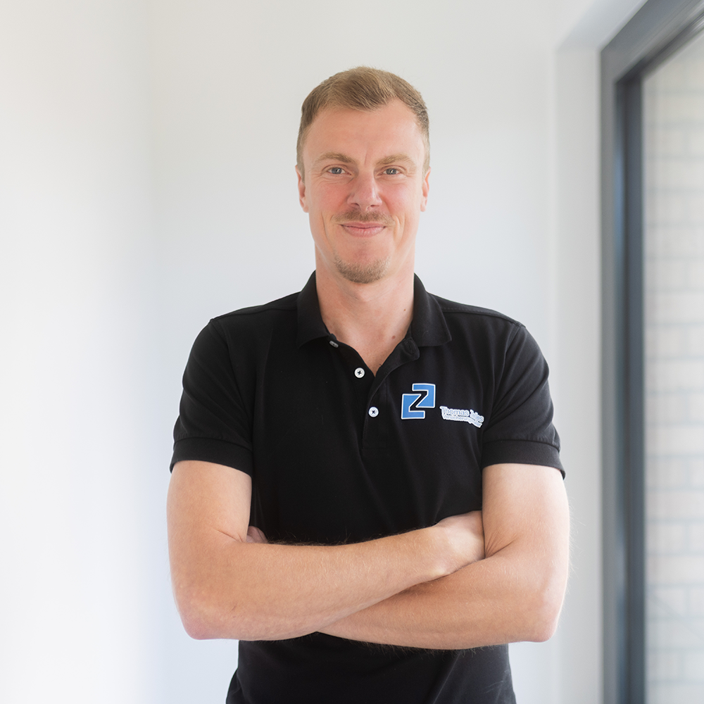 Thomas Zelles steht vor einer weißen Wand